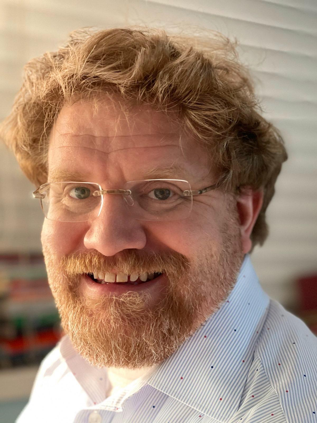 a close up of a person wearing glasses and a beard.