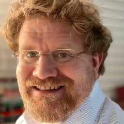 a close up of a person wearing glasses and a beard.