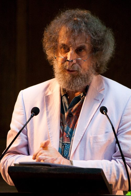 a man with a beard and glasses standing at a podium.