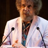 a man with a beard and glasses standing at a podium.