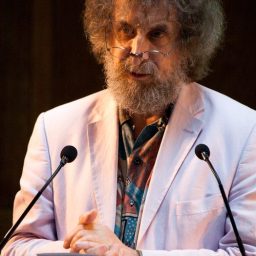 a man with a beard and glasses standing at a podium.
