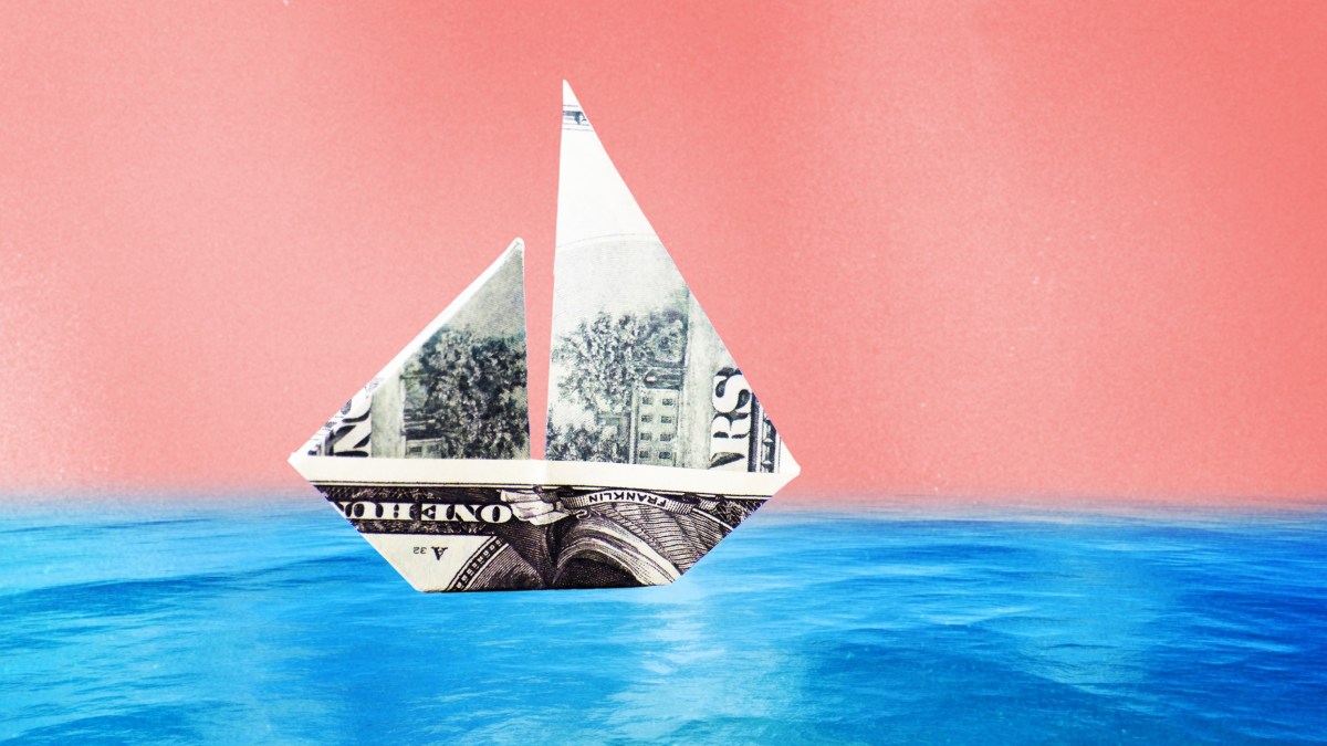 a dollar bill origami boat floating in the ocean.