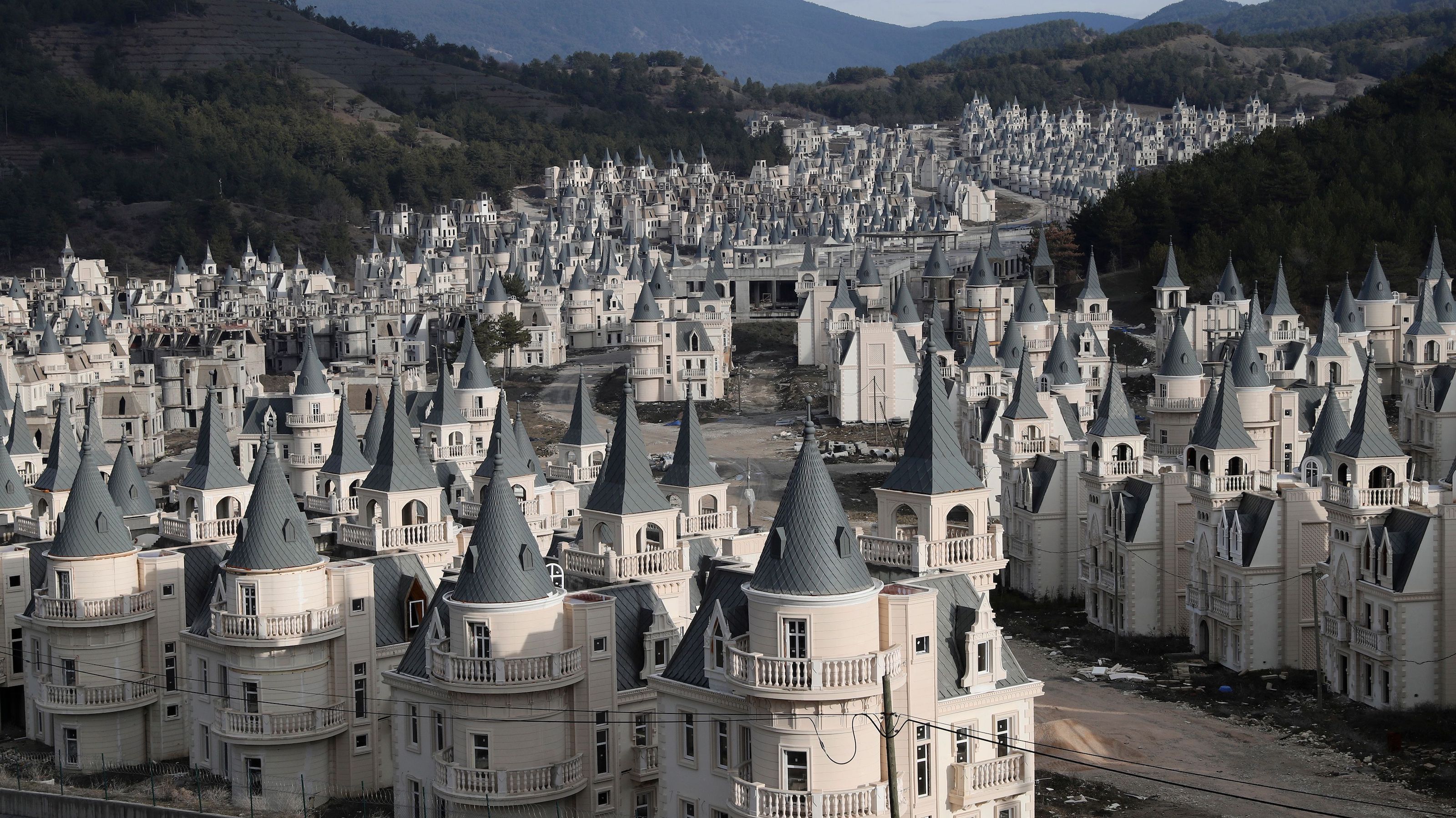 an aerial view of a castle like area with mountains in the background.