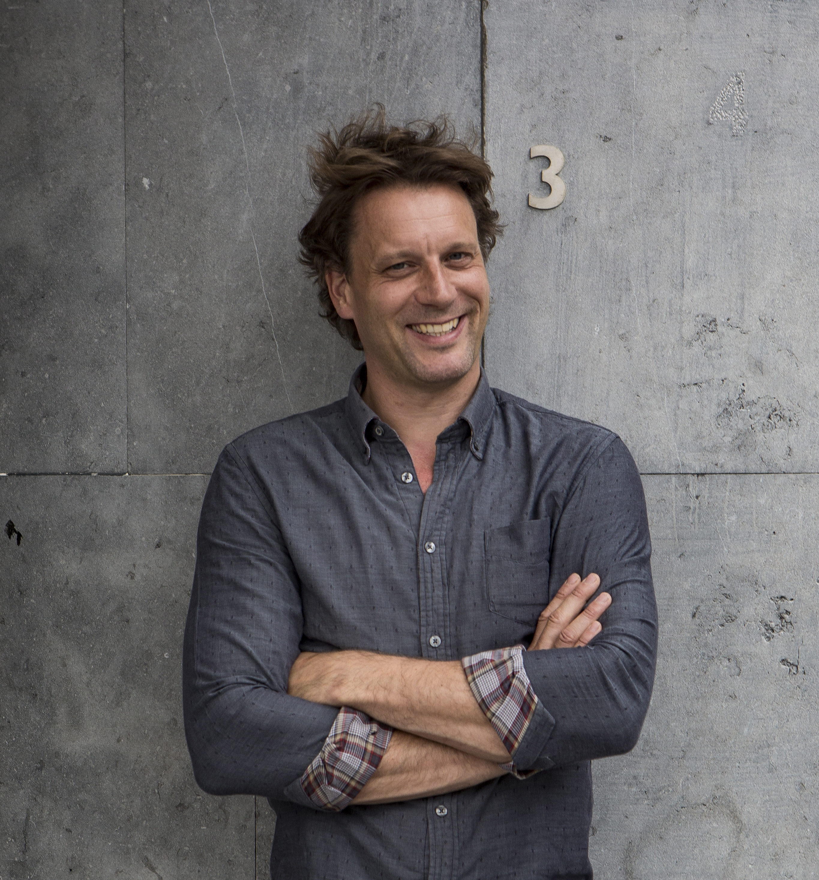 a man standing with his arms crossed in front of a wall.