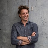 a man standing with his arms crossed in front of a wall.