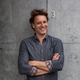 a man standing with his arms crossed in front of a wall.