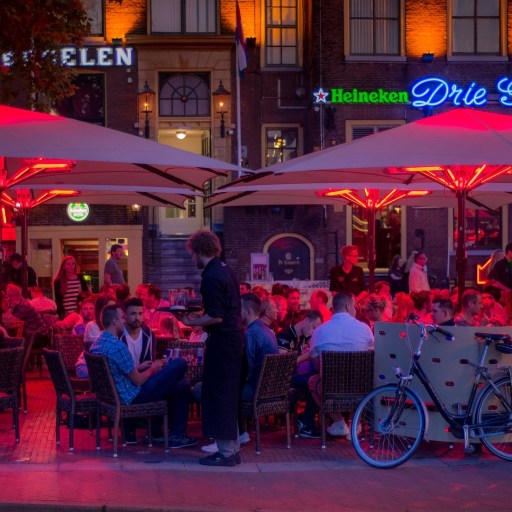 a group of people sitting at tables under umbrellas.