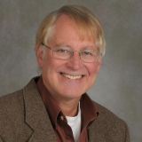 a man with glasses smiling for a picture.