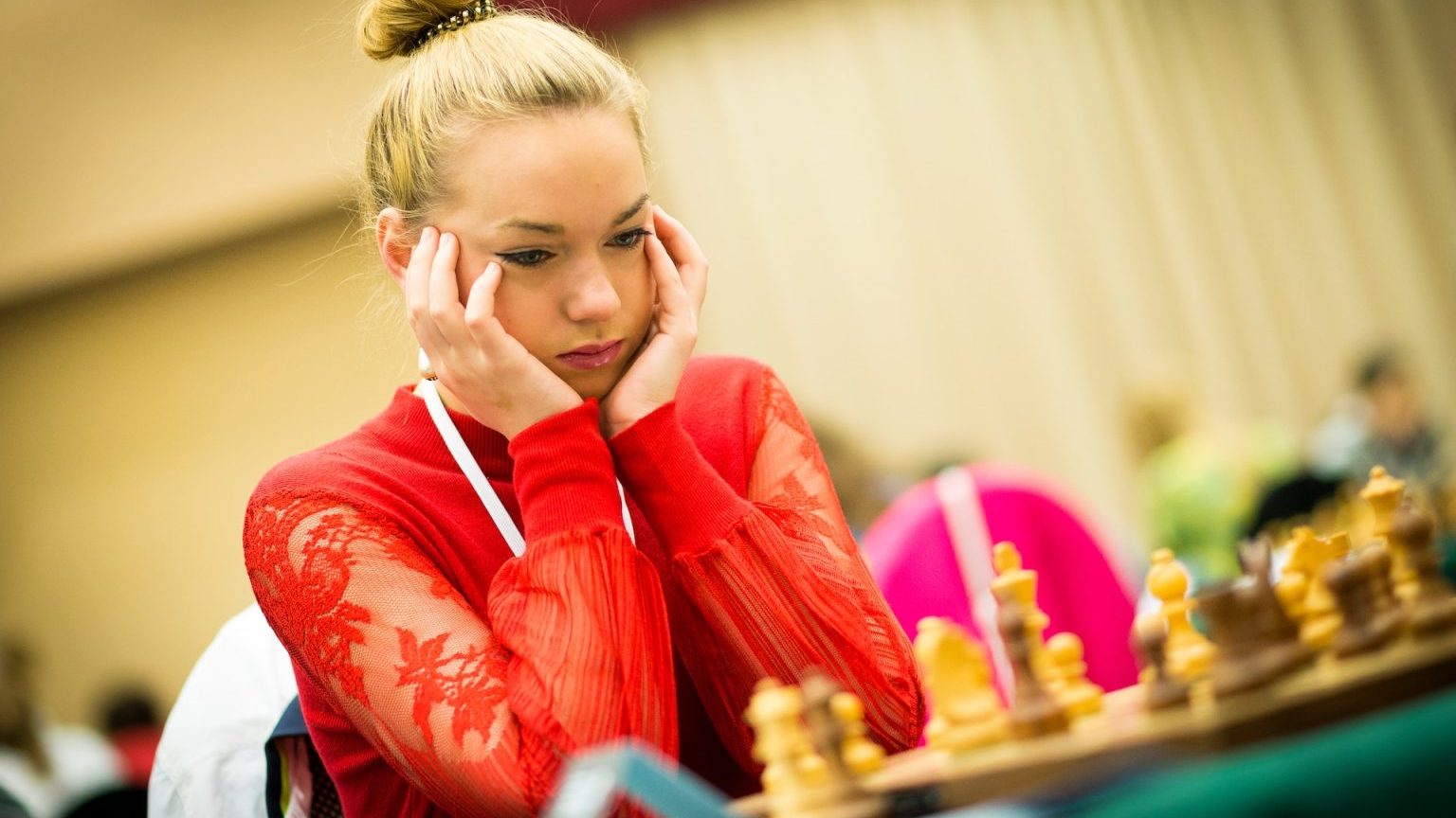 a woman sitting at a table with a chess board.