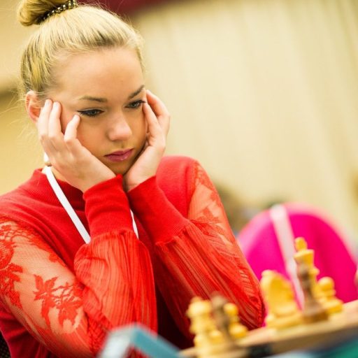 a woman sitting at a table with a chess board.