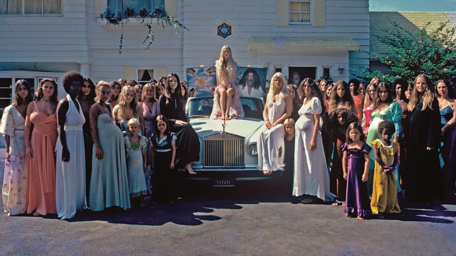 a group of people standing in front of a car.