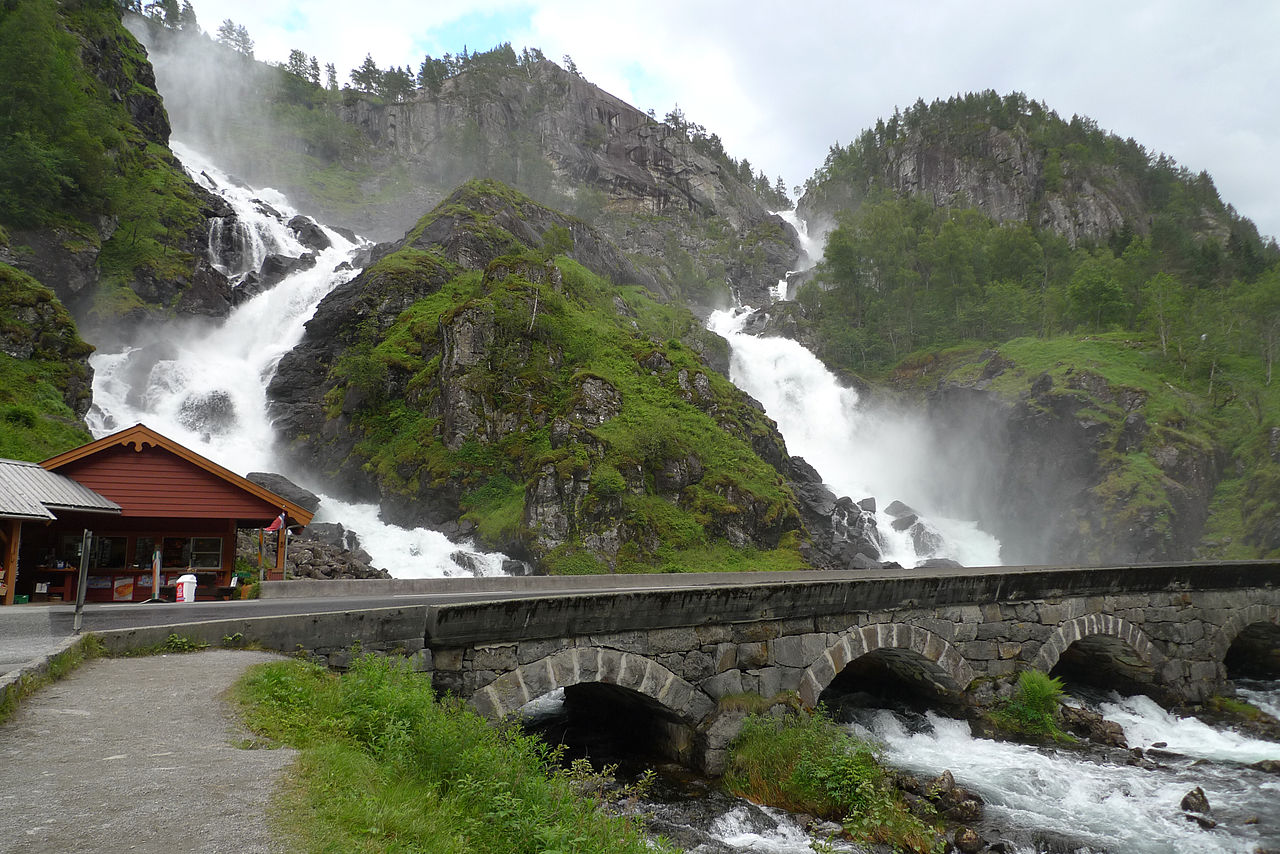 a bridge over a river with a waterfall in the background.