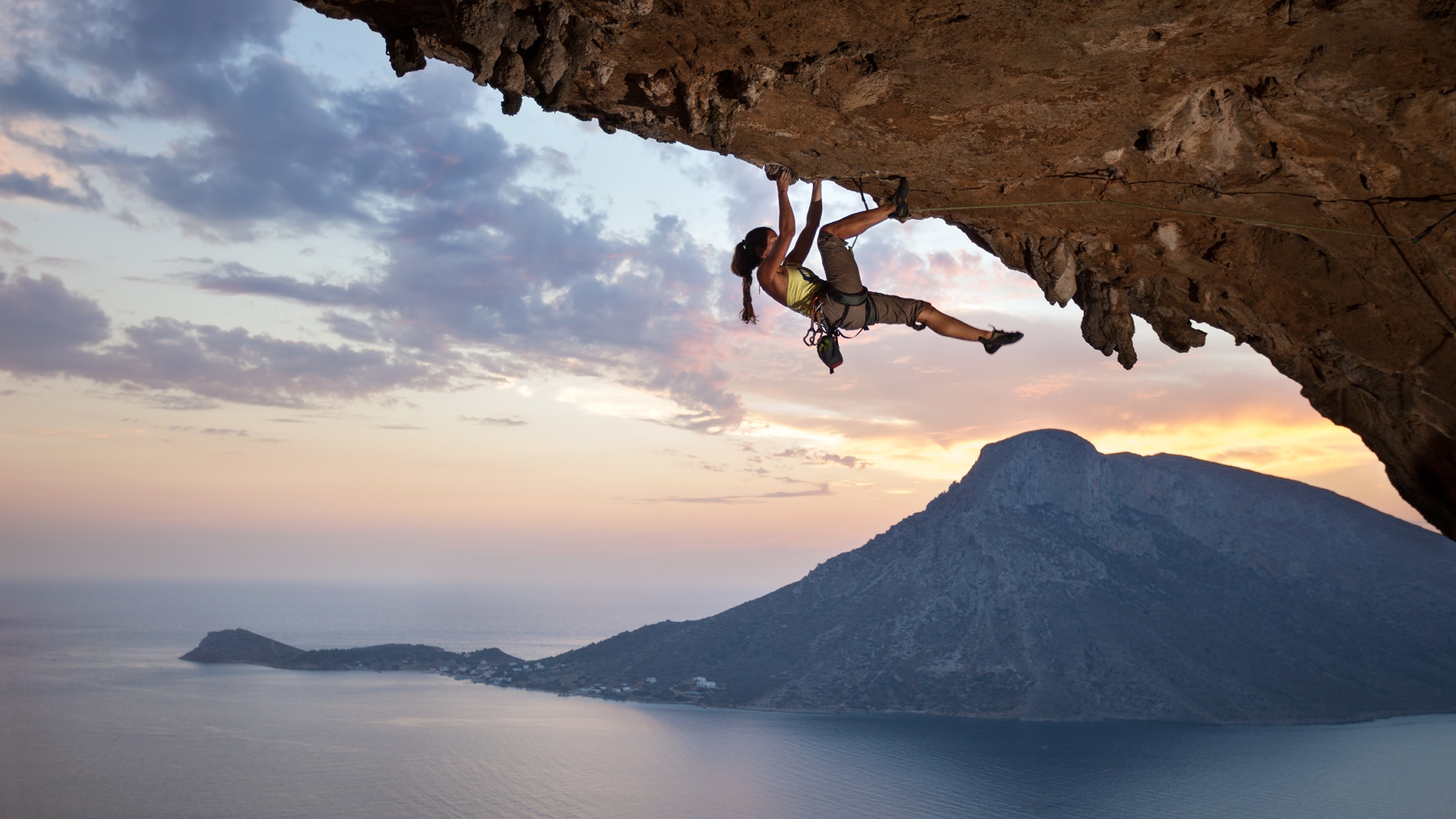 A woman climbing up the side of a mountain.