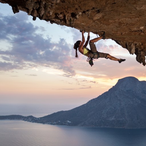 A woman climbing up the side of a mountain.