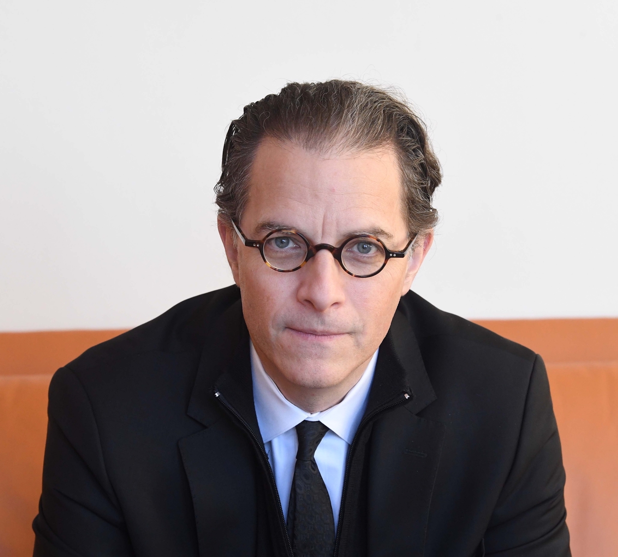 a man in a suit and tie sitting on a couch.