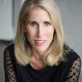 a woman with blonde hair wearing a black top.