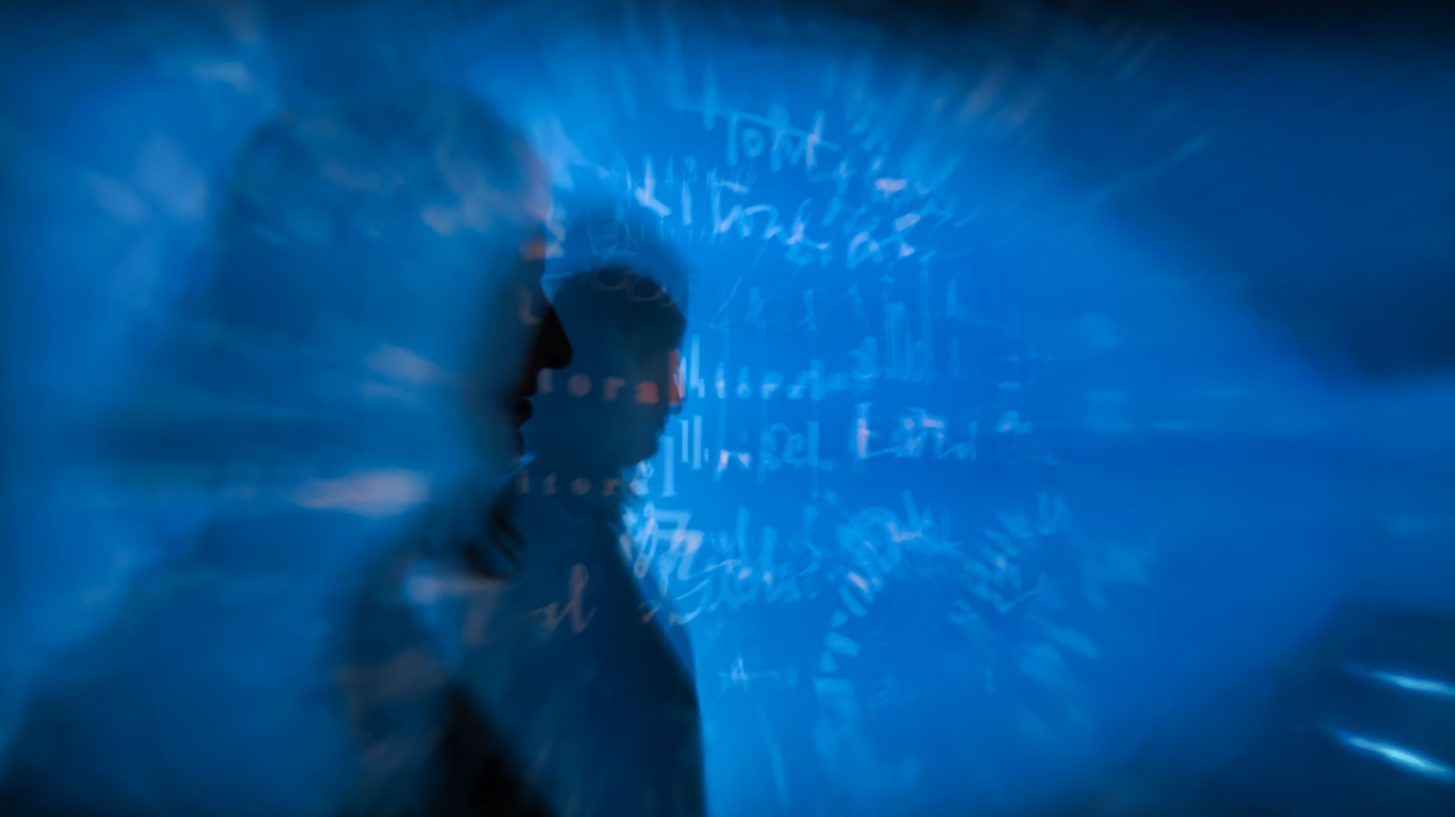 a blurry image of a man standing in front of a blue background.