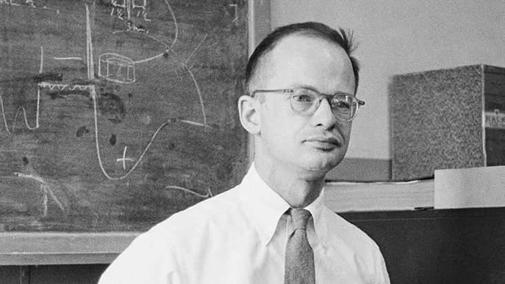 a man standing in front of a blackboard with writing on it.