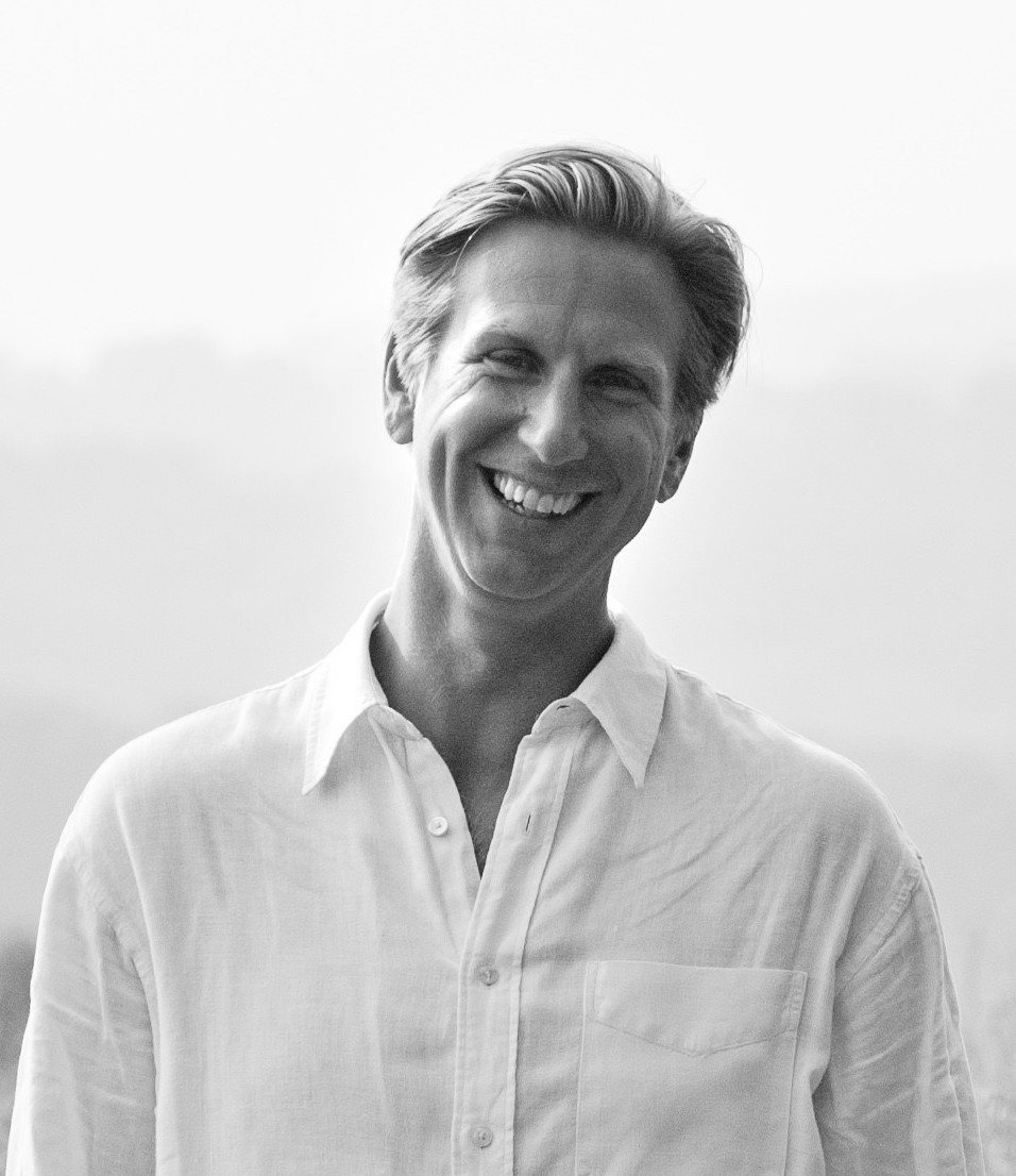 a black and white photo of a smiling man.