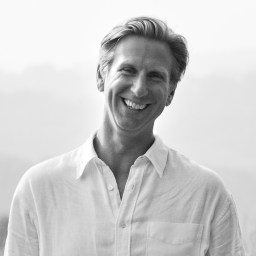 a black and white photo of a smiling man.