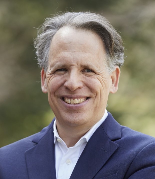 a close up of a person wearing a suit and smiling.