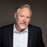 a man with a beard and a blue shirt.