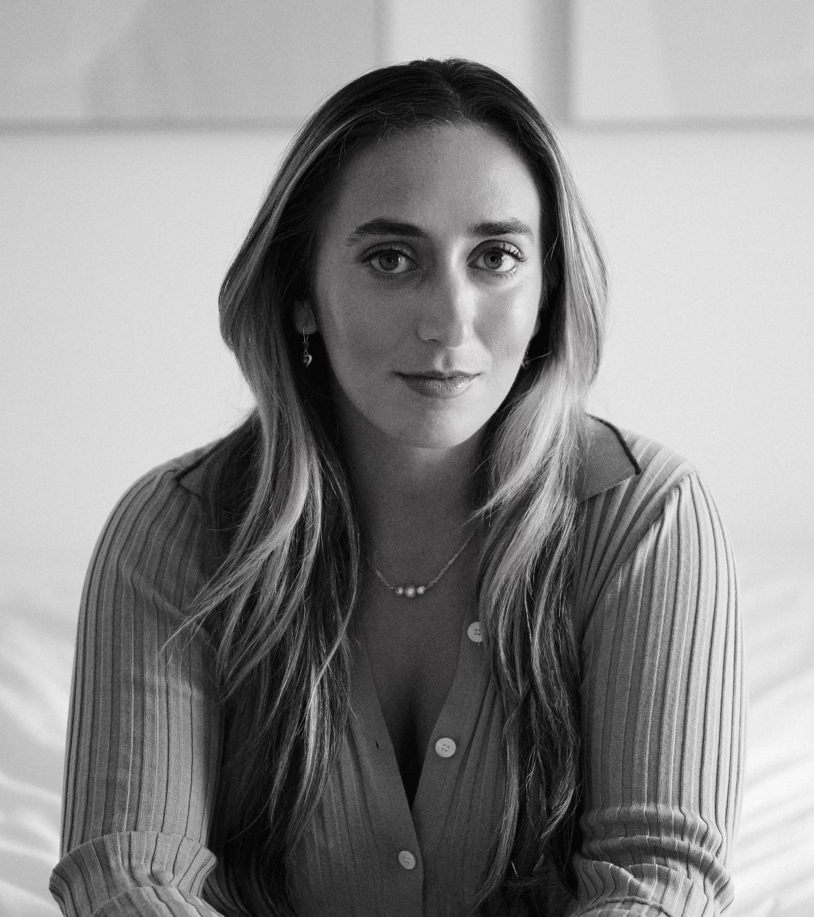 a black and white photo of a woman sitting on a bed.