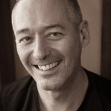 a black and white photo of a man smiling.