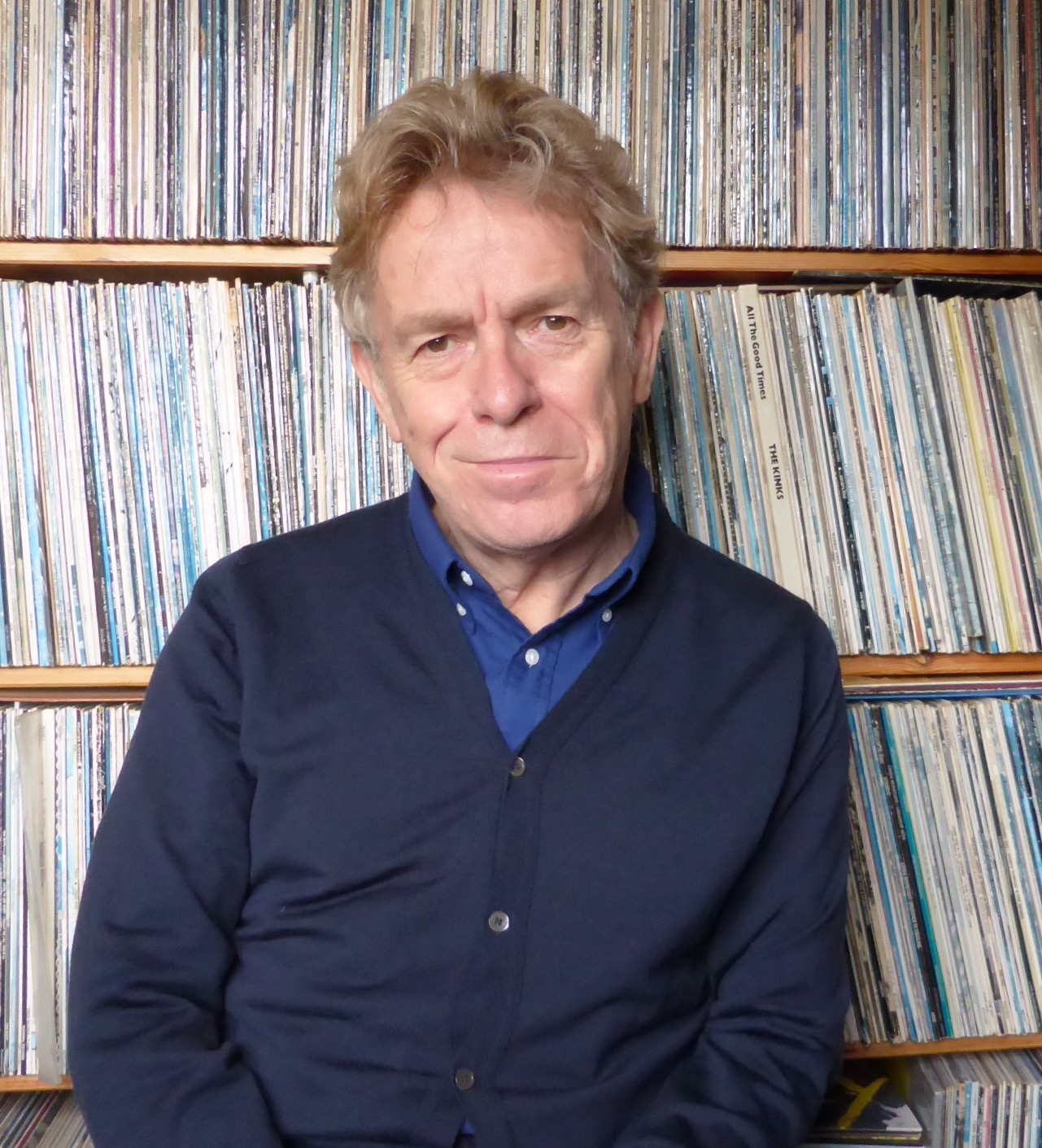 a man sitting in front of a shelf full of records.