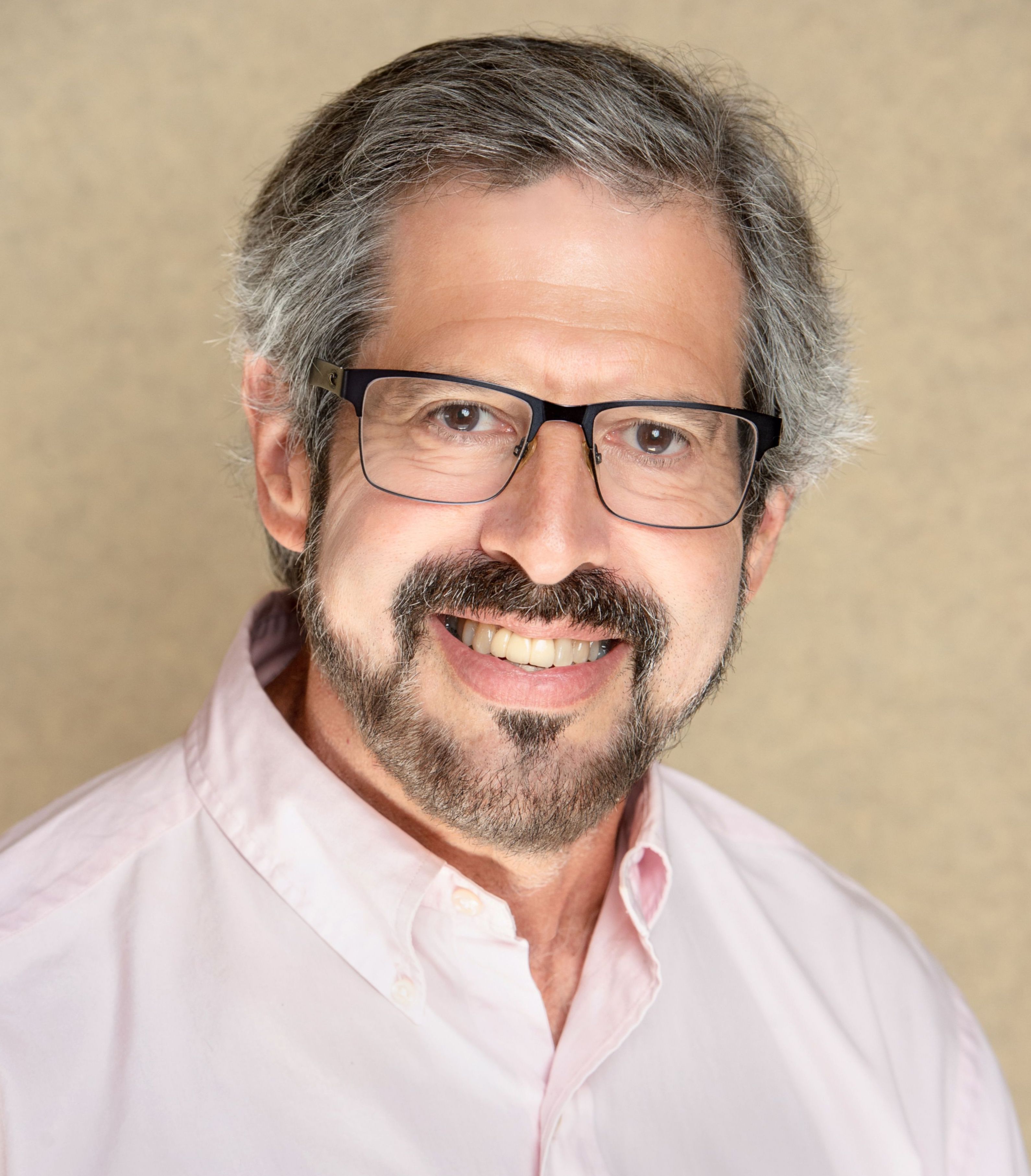 A man wearing glasses and a pink shirt.