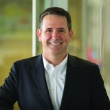 a man smiling in a business suit.