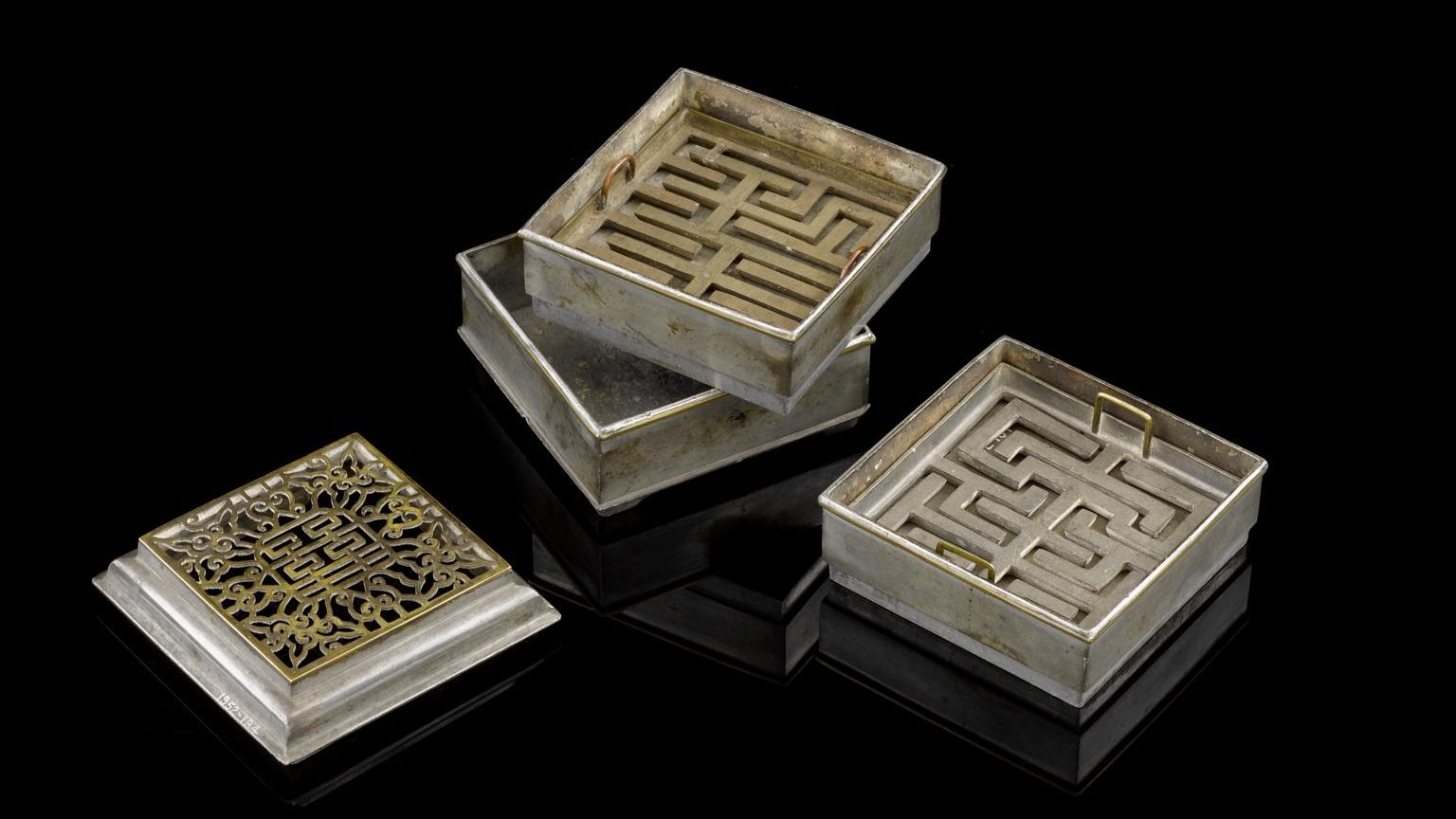 Three silver boxes with designs on them.