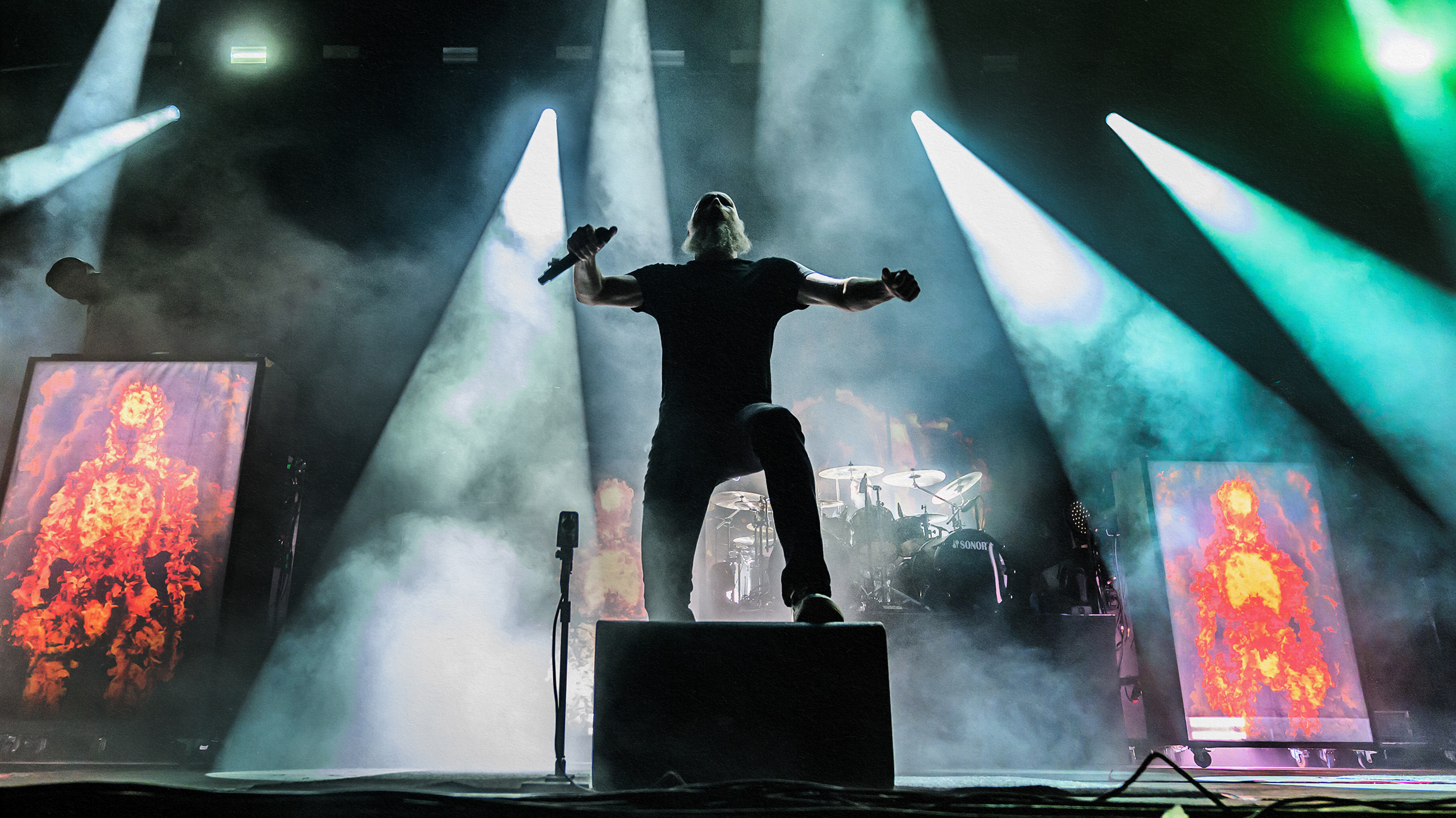 A heavy metal performer with smoke-emitting eyes on stage.