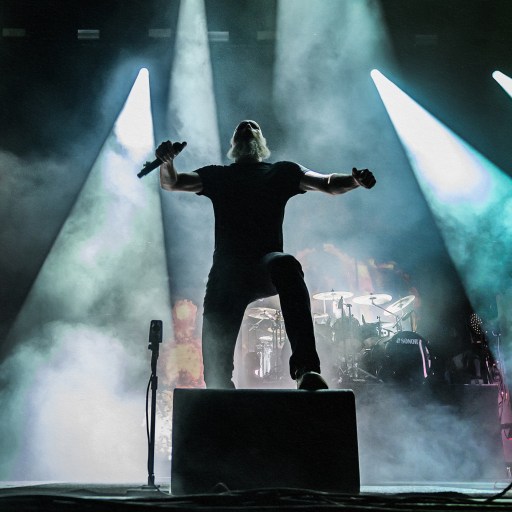 A heavy metal performer with smoke-emitting eyes on stage.