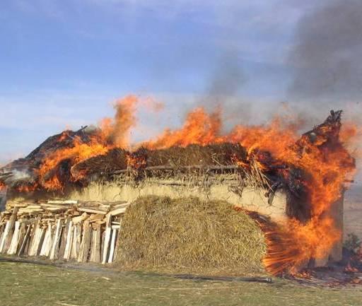 A burning house in a field.