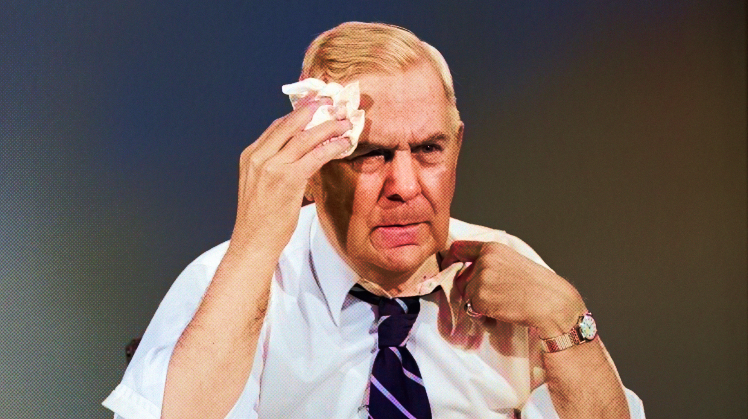 A man in a tie is holding a tissue to his face.