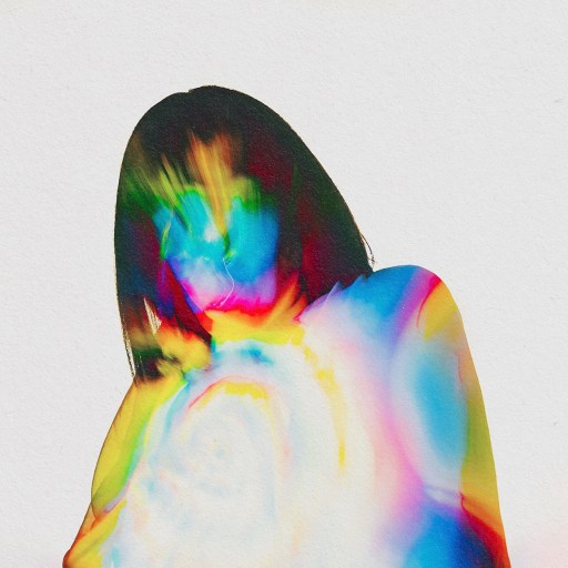 A woman in a vibrant dress is standing against a minimalist backdrop.