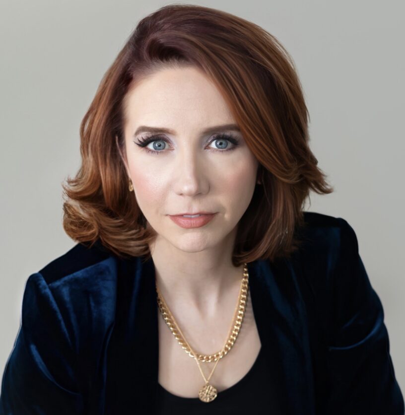 A woman wearing a black jacket and gold necklace.