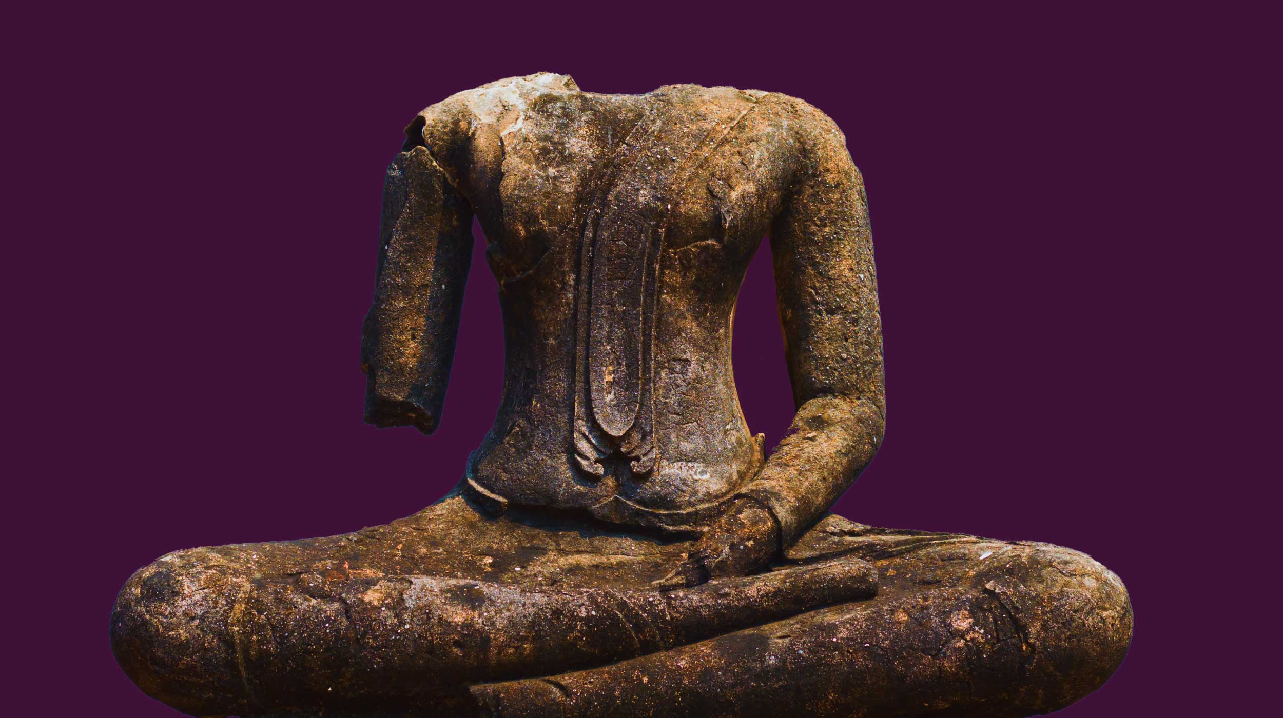 Ancient headless stone Buddha statue with one arm missing, seated cross-legged against a solid dark purple background.