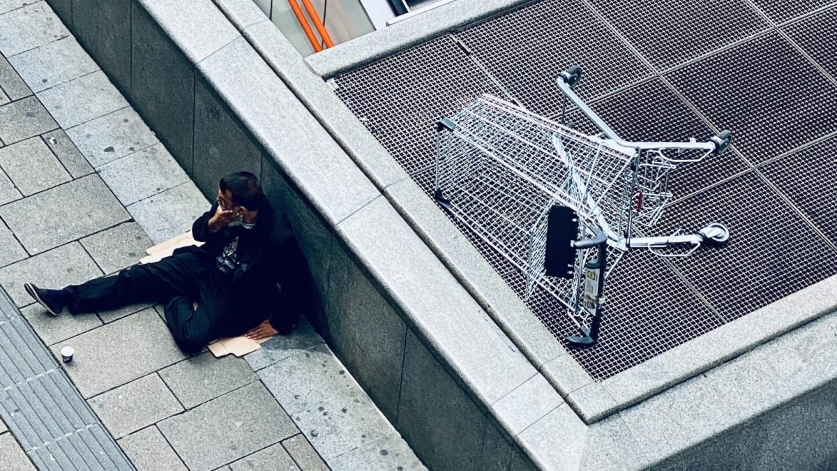 A man is laying on the ground next to an escalator.