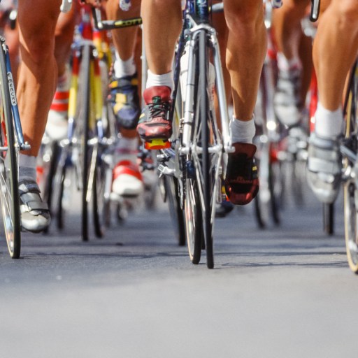 A group of cyclists riding down the road.