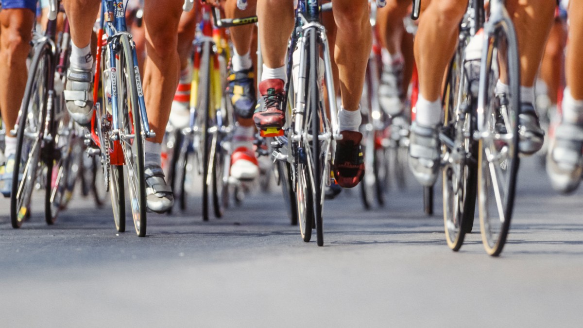 A group of cyclists riding down the road.