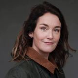 A woman in a brown jacket posing for a photo.