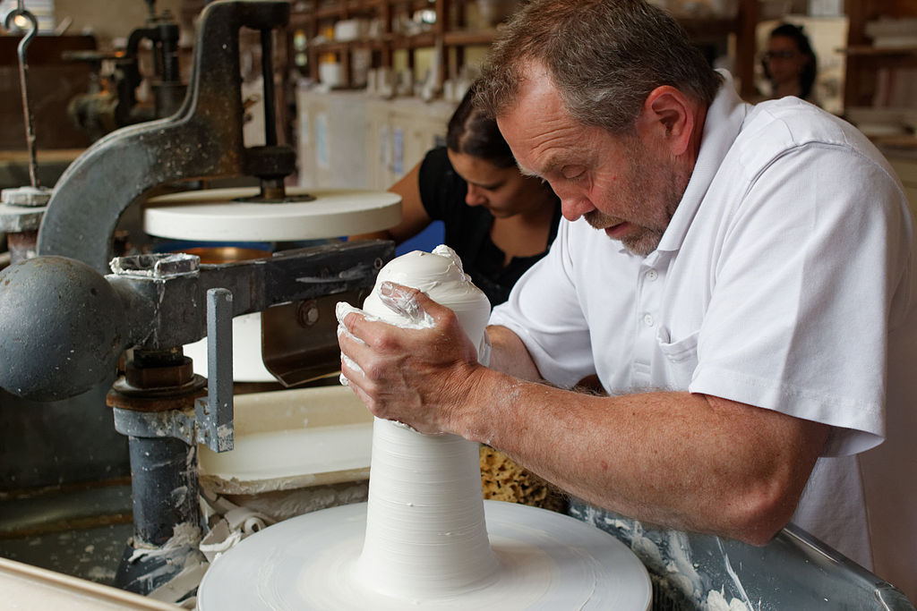 A man working on a pottery wheel in a factory.