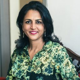 A woman in a green floral shirt sitting on a chair.