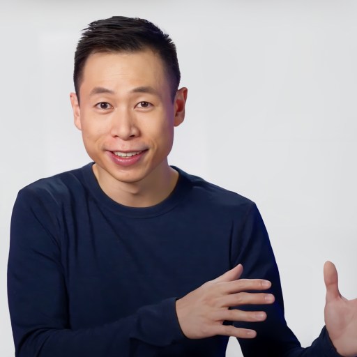 A man in a blue shirt with his hands outstretched.