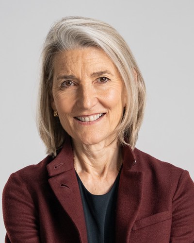 A woman in a burgundy jacket smiling.