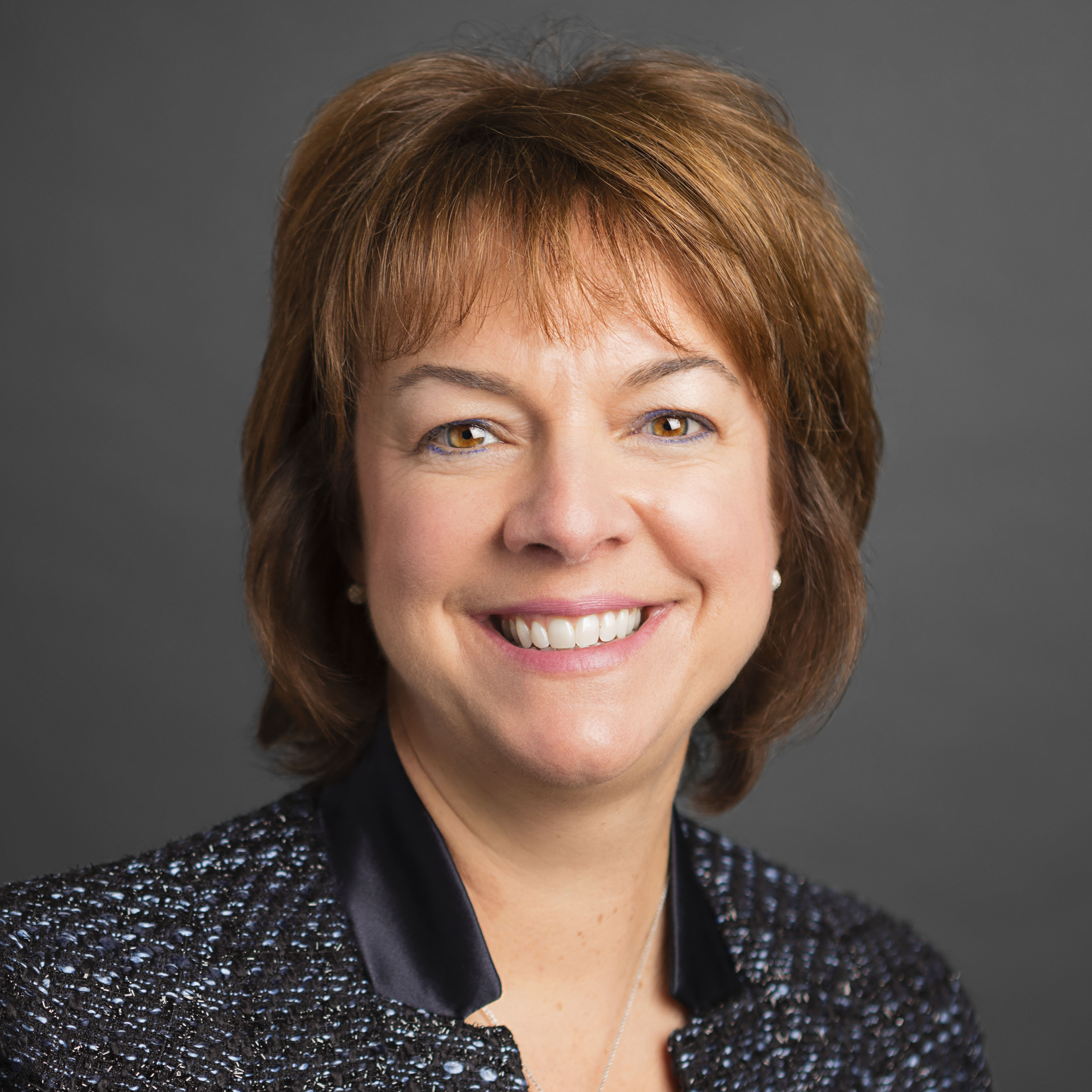 A woman in a black jacket smiling for the camera.