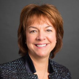 A woman in a black jacket smiling for the camera.