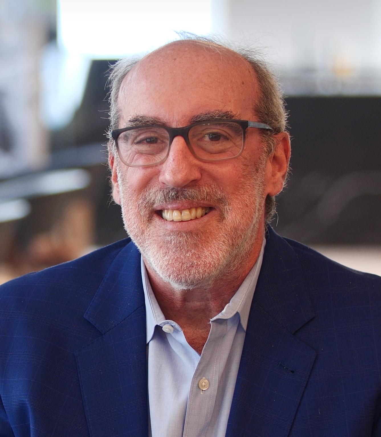 A man wearing glasses and a blue jacket.
